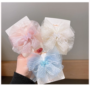 Close-up of pink, white, and blue chiffon bow hair clips on display cards for girls