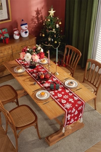 Detailed view of red Christmas table runner with white snowflake patterns and tassels