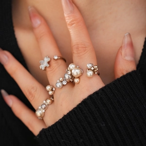 Detailed close-up of a stacked set of silver rings with pearls, zircon, and a bear motif