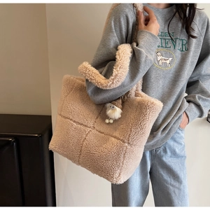 Detailansicht der beigen gesteppten Lammfell-Tasche mit süßem Plüschpuppen-Anhänger