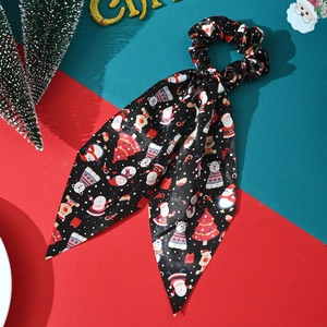 Detail of Christmas satin scrunchie with streamer featuring Santa and reindeer patterns