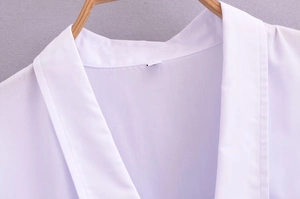 Detail view of the elegant deep V-neckline and breathable fabric texture on a white blouse