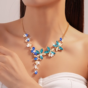 Detailed view of luxury floral necklace with blue crystals and leaf tassel on model neck