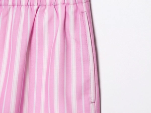 Detailed macro view of pink striped shorts featuring elastic waistband and side pockets