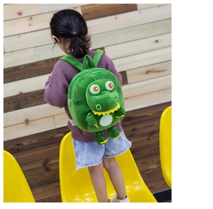 Rear view of a child wearing a soft green plush dinosaur backpack in a cozy room