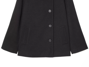 Detail view of the hem on a black wool coat showing three buttons and side pockets
