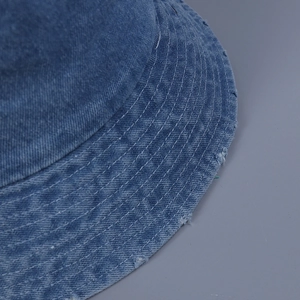 Détail d'un bob en jean délavé bleu clair avec bords effilochés et surpiqûres blanches