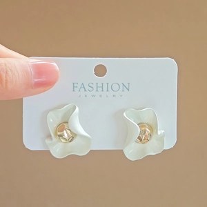 Close-up of floral earrings with white matte petals and golden textured metal center