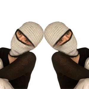Macro detail of hand-knitted balaclava mask with contrasting black stitching around eyes