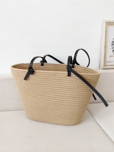 Beige woven cotton rope tote bag with black shoulder straps for beach and vacation use
