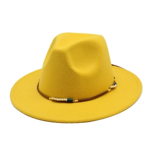 Dettaglio del cappello in lana gialla con fascia intrecciata e accenti di perline