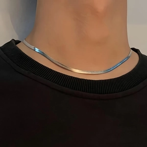 Close-up of minimalist silver snake bone chain necklace worn on model's neck
