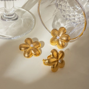 18k gold plated stainless steel flower jewelry set with crystals on beige surface