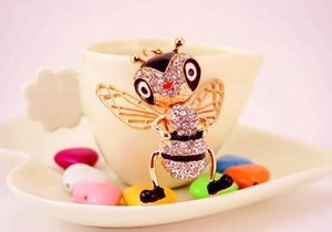 Close-up of golden bee keychain with sparkling rhinestones on a decorative heart dish
