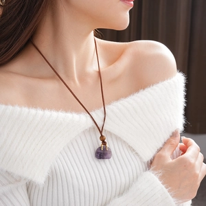 Macro view of purple stone pendant necklace on a model wearing white sweater