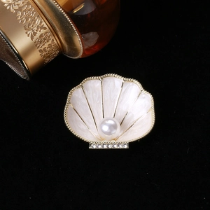 Detail of shell brooch with enamel inlay, a central pearl, and rhinestone accents