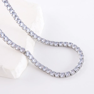 Collier tennis argenté serti de cristaux blancs sur un fond blanc minimaliste épuré