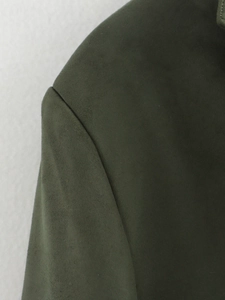 Detail of fine stitching and dark green faux suede texture on a blazer shoulder