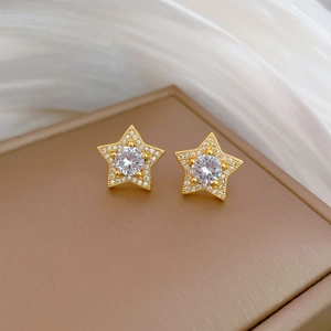 Macro shot of gold star stud earrings with central zircon and pave-set diamonds