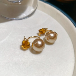 Detail of champagne pearl and amber crystal earrings with 18K gold plated metal