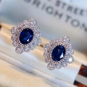 Detail of vintage halo earrings with blue zircon and pavé diamonds in silver metal