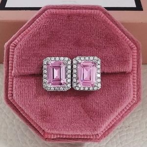 Macro view of emerald-cut pink gemstone earrings with zircon halo in a velvet box