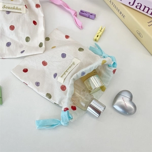 Detailed view of polka dot drawstring bag with skincare bottles and Sozakka label