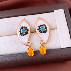 Detailed close-up of vintage earrings with a blue heart stone and an orange teardrop gem