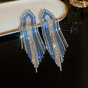Close-up of sparkling rhinestone tassel earrings with blue to silver gradient chain fringe