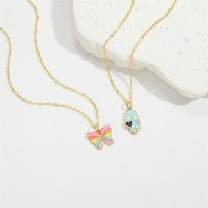 Collier croix doré avec pendentifs papillon coloré et main de Hamsa bleue sur fond blanc