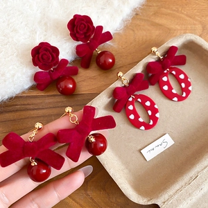 Détail de boucles d'oreilles nœuds rouges floqués avec breloques rose et perle d'hiver