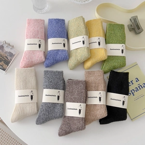 Thick knit wool crew socks in ten pastel colors arranged on a white table