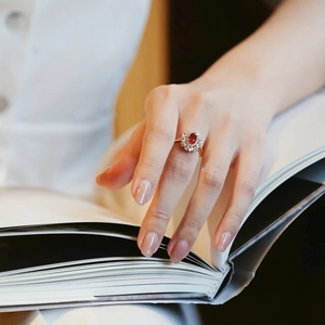 Vintage rose gold ring featuring an oval ruby and diamond halo on a finger