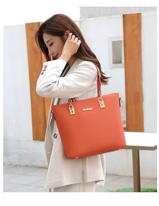 Detail of vibrant orange tote bag with golden hardware and textured PU leather