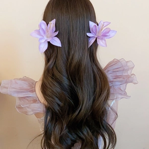 Detail of purple fabric hibiscus flower clips on long wavy hair for romantic styling