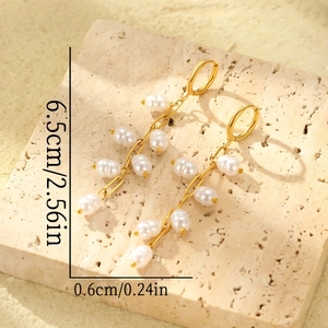 Elegant gold fringe earrings with baroque pearl clusters hanging on stone pedestal