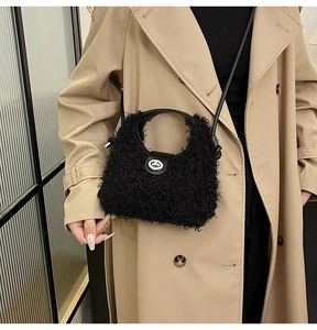 Detail of black teddy plush dumpling bag with silver metal lock and leather handle