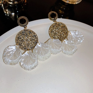 Vue détaillée de boucles d'oreilles dorées vintage avec glands de pétales blancs