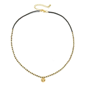 Close-up of beaded necklace with grey beads, gold spacers and a textured coin pendant