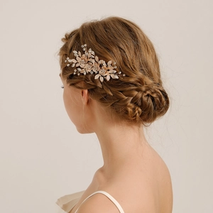 Elegant gold bridal hair comb with crystal flowers and pearls shown on a bun hairstyle