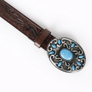 Detail of western leather belt buckle with embossed metal and turquoise stone