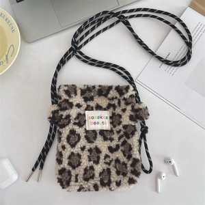 Détail d'un petit sac bandoulière en peluche léopard avec cordon et étiquette logo