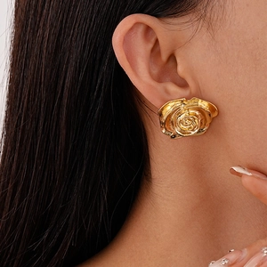 Gros plan d'une boucle d'oreille rose en métal doré portée à l'oreille avec détails