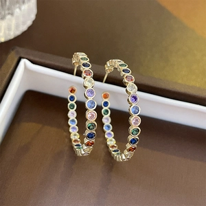 Detail of gold hoop earrings with multi-colored zircons displayed on a jewelry box