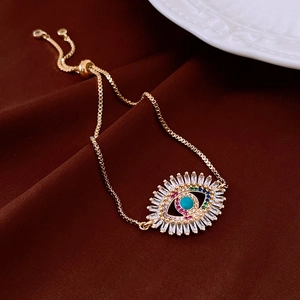 Macro shot of gold vintage evil eye bracelet with colorful zircons on dark fabric