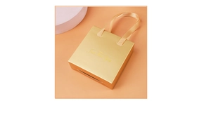 Detail of luxury gold gift box with silk handles and Just For You metallic gold lettering
