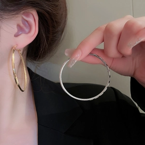 Detailed macro view of large gold and silver hollow hoop earrings with starlight matte finish