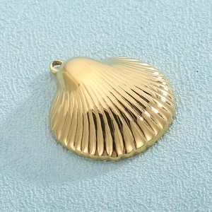 Close-up of golden hollow scallop pendant with textured finish and hanging ring
