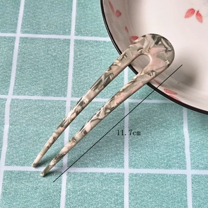 Detail view of marble pattern U-shaped hair pin measuring 11.7cm on green cloth