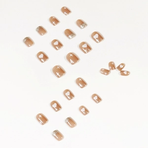 Short nude press-on nails with white hearts, star patterns and silver glitter tips